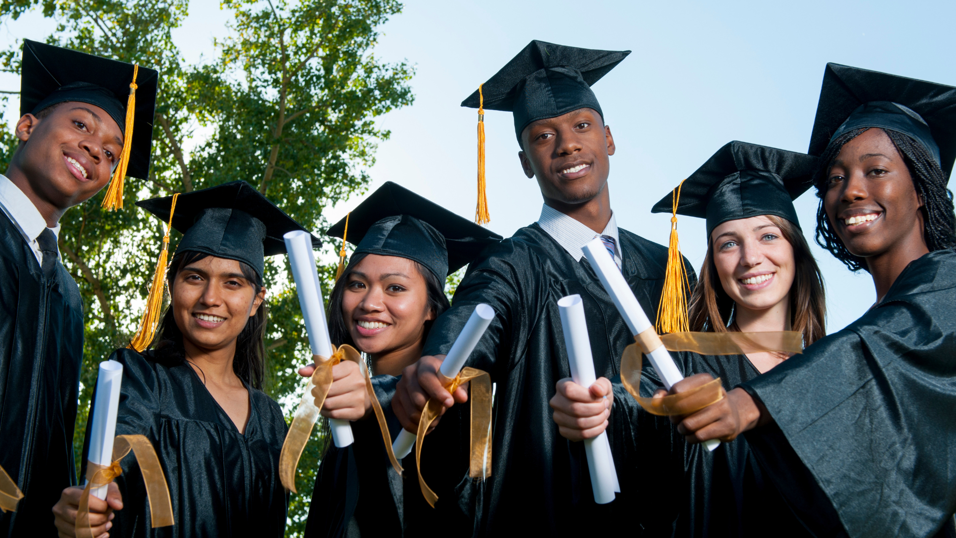 Smiling graduates holding diplomas